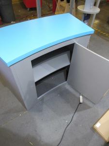 VK-1334 Modular Exhibit with Closet Storage, Reception Counter w/ Storage, MOD-1453 Bistro Table with Wireless Phone Charging, and MOD-1431 Charging Tower with Graphics