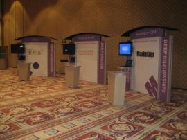 RENTAL Exhibit -- Pavilion with multiple 10&rsquo; exhibits, arch-shape canopies with black covers, Sintra accent wings, tapered counter workstations, 16&rsquo; high exhibits, kiosks -- Image 2