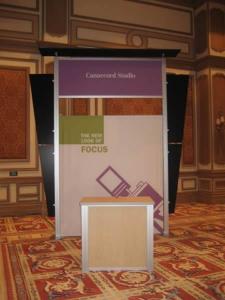 RENTAL Exhibit -- Pavilion with multiple 10&rsquo; exhibits, arch-shape canopies with black covers, Sintra accent wings, tapered counter workstations, 16&rsquo; high exhibits, kiosks -- Image 5