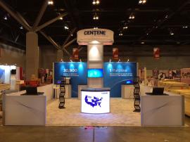 RENTAL: Island with 12' High Tower with Storage Closet, Hanging Sign, (12) Arm Lights, (3) RE-1202 Rectangular Counters, (2) RE-1219 Square Pedestals, (1) RE-703 Charging Station, (1) RE-1250 Reception Counter with Backlit Graphic, (2) RE-171 Literature S