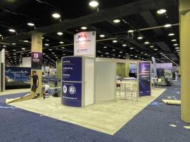 RENTAL: RE-9049 Island Design with Direct Print Sintra Graphics, Large Monitor Mount and 55" Monitor, Attached Tower Counter, and Client&rsquo;s Existing Reception Counter.