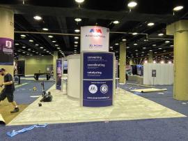 RENTAL: RE-9049 Island Design with Direct Print Sintra Graphics, Large Monitor Mount and 55" Monitor, Attached Tower Counter, and Client&rsquo;s Existing Reception Counter.